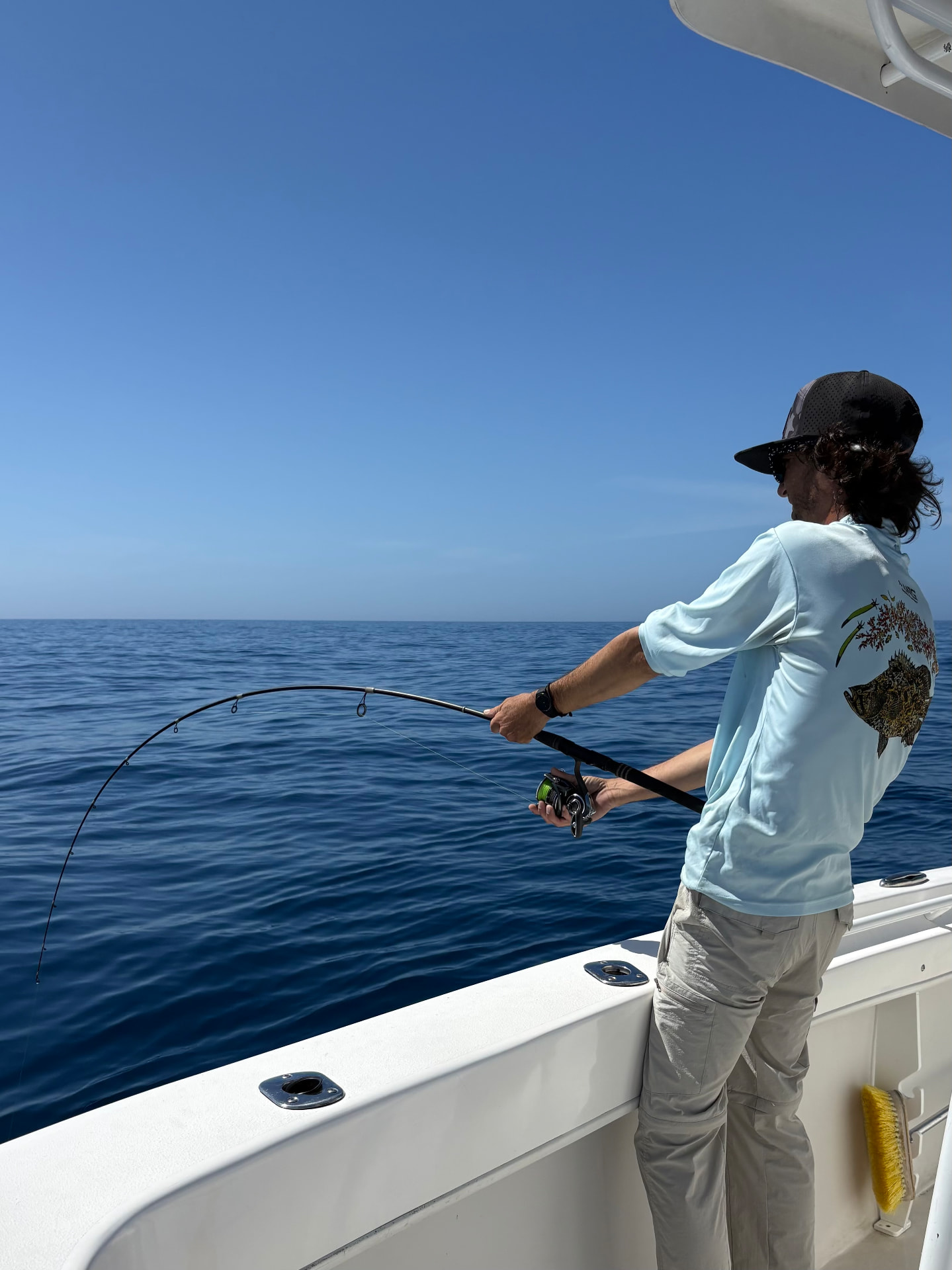 Fishing gear in action — rod bent and reel screaming as a guest fights a fish on a Florida Fisherman Charters trip